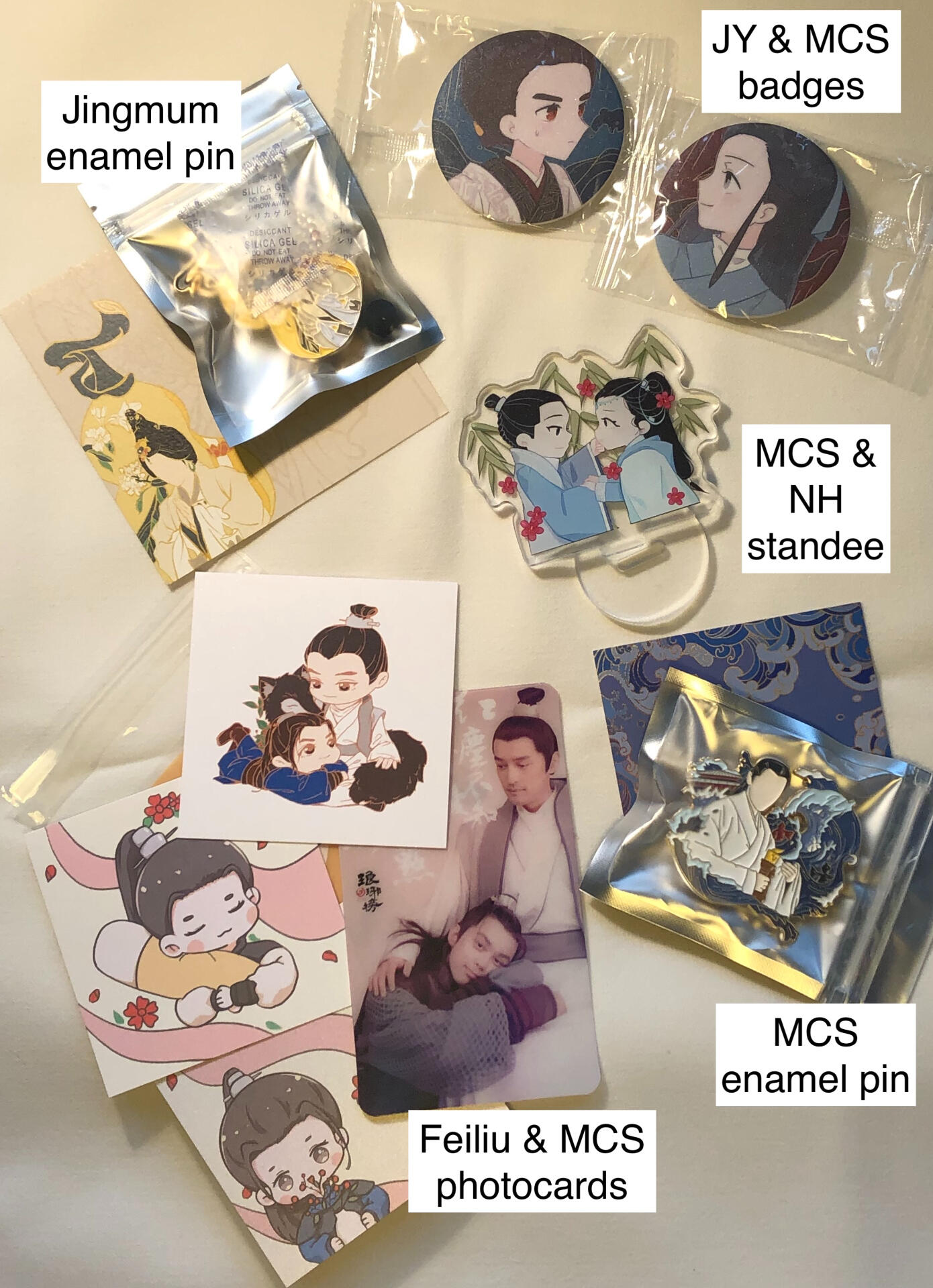 Various Nirvana in Fire related items including enamel pins, photocards, an acrylic standee and a couple of badges.